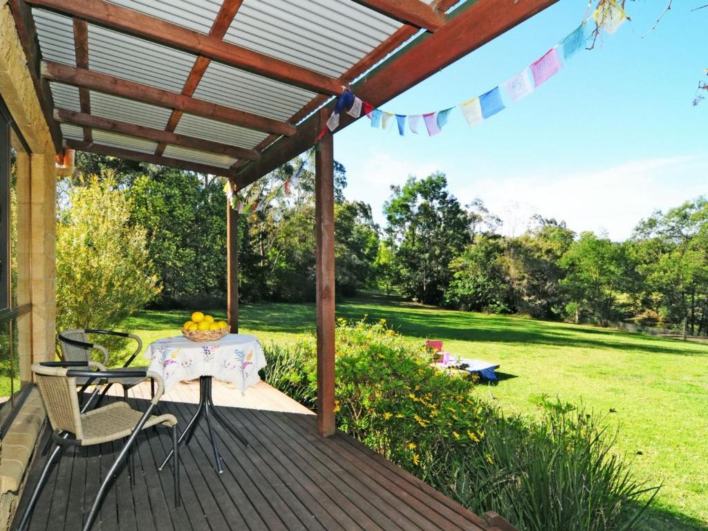 a patio with a table and chairs on a deck at Sweet Gum Bend Delightful 2 bedroom cottage in Kangaroo Valley