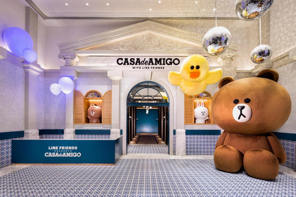 un oso de peluche marrón grande sentado frente a una tienda en LINE FRIENDS presents CASA DE AMIGO, en Macau