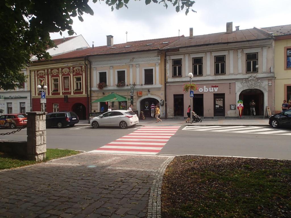 a city street with cars parked in front of a building at Penzión a Reštaurácia u Jeleňa in Stará Ľubovňa