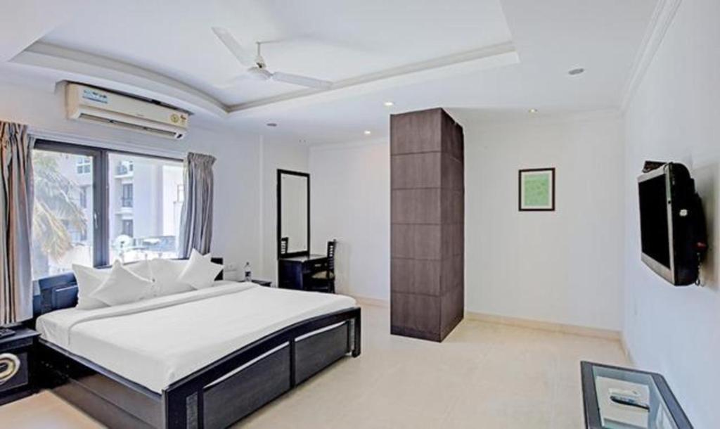 a bedroom with a bed and a flat screen tv at FabHotel Skyry in Chennai