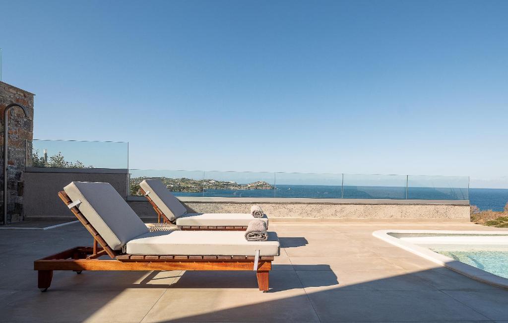 a pair of lounge chairs sitting on a patio next to a pool at Ligaria Mare in Agia Pelagia