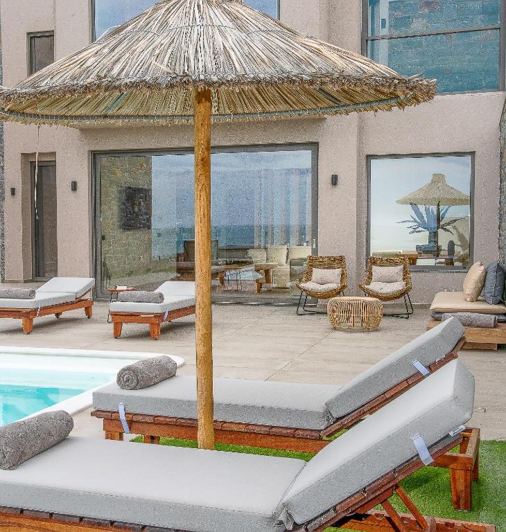 a patio with an umbrella next to a swimming pool at Ligaria Mare in Agia Pelagia