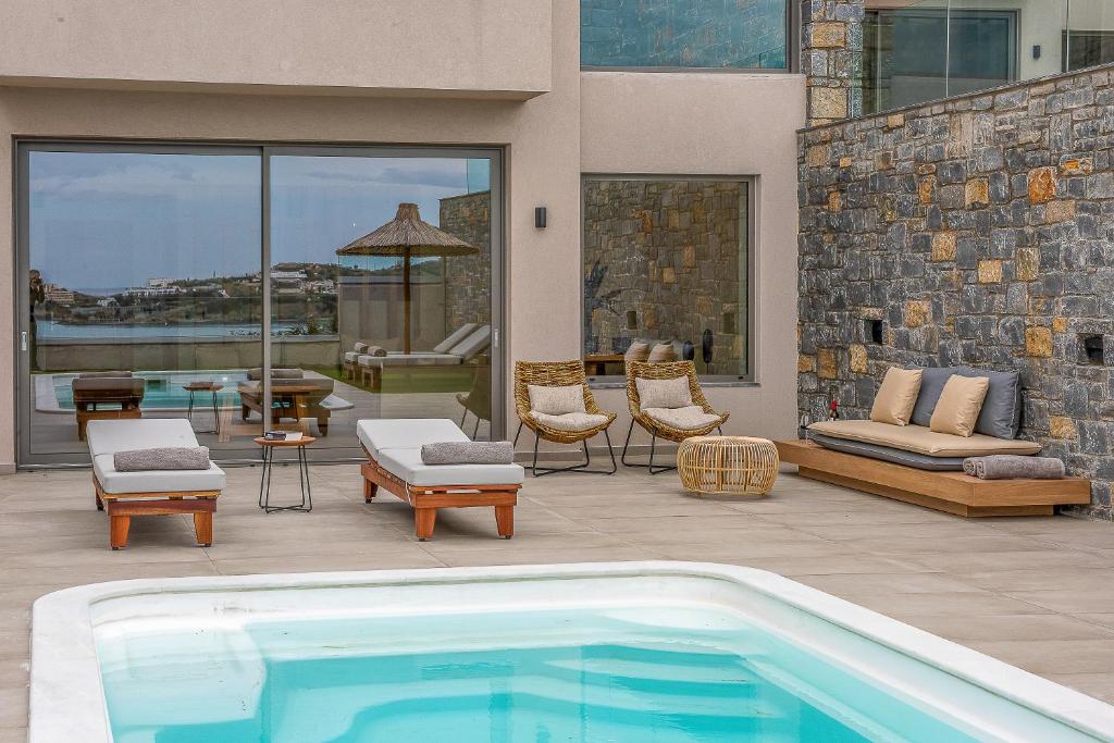 a patio with a swimming pool and chairs and a patio with at Ligaria Mare in Agia Pelagia