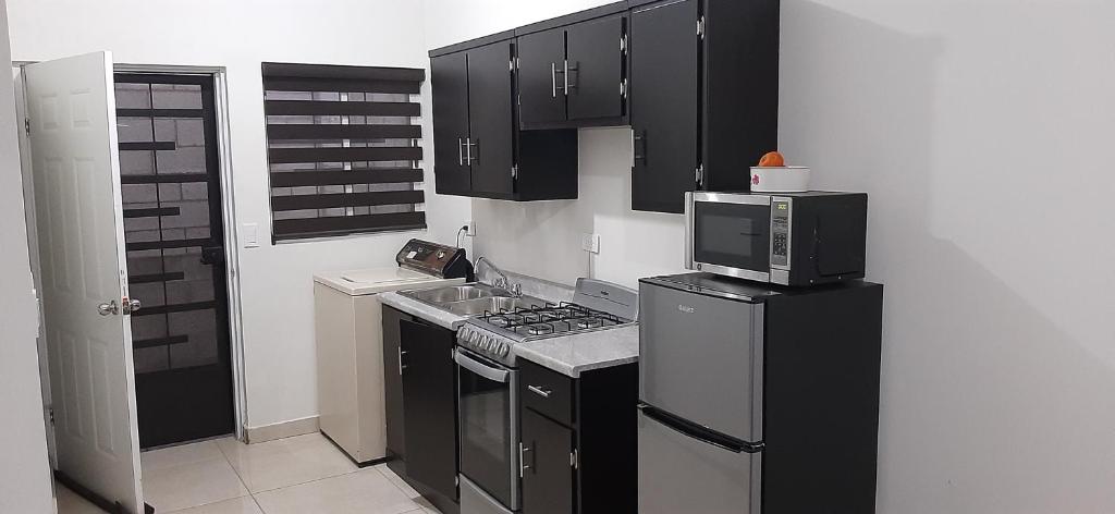 una pequeña cocina con armarios negros y microondas en Casa Mina la prieta, en Hidalgo del Parral