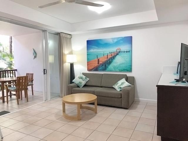 ein Wohnzimmer mit einem Sofa und einem Tisch in der Unterkunft REEF RETREAT APARTMENTS PALM COVE Unit 11 in Palm Cove