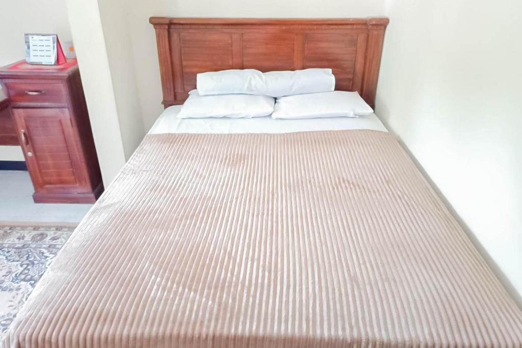1 cama con cabecero de madera y almohadas blancas en TRIYOGA Homestay Syariah RedPartner, en Sangkanurip
