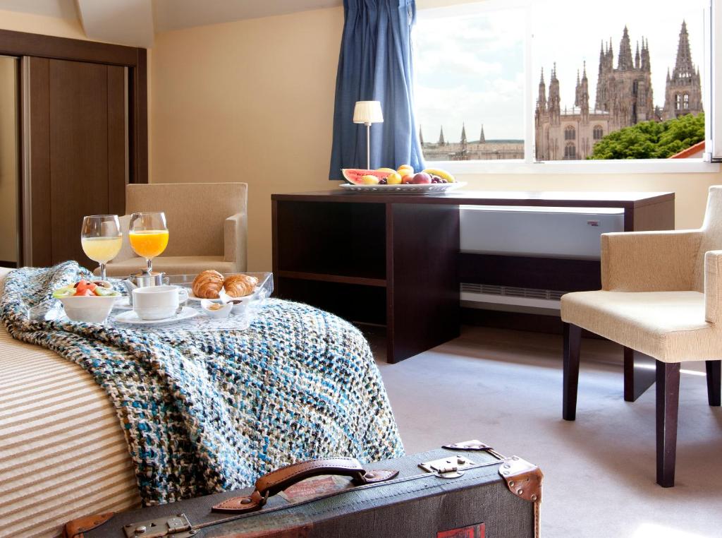 Habitación de hotel con cama con mesa y copas de vino en Palacio de los Blasones Suites, en Burgos