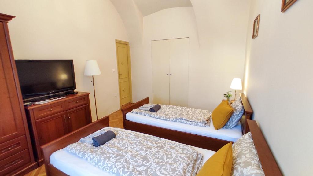 mały pokój z 2 łóżkami i telewizorem z płaskim ekranem w obiekcie Theatroom Apartman w Egerze