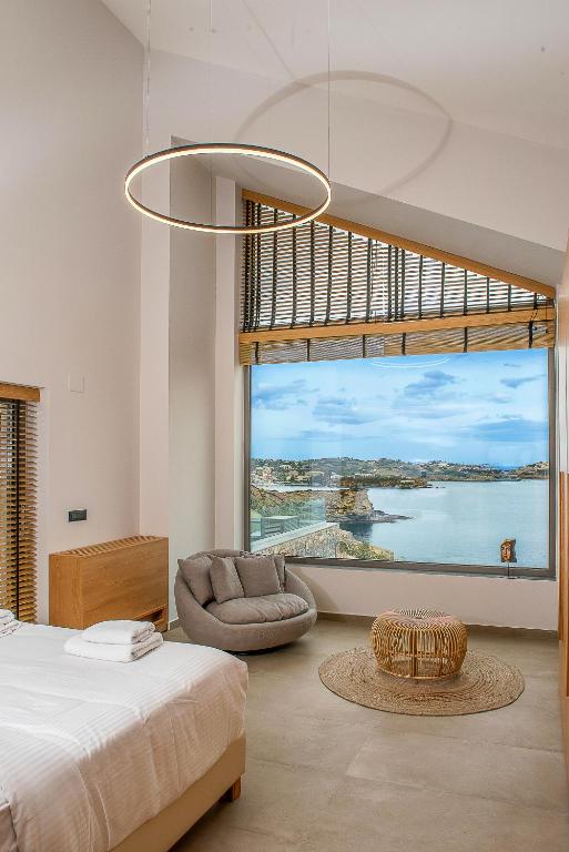 a bedroom with a large window with a bed and a chair at Ligaria Mare in Agia Pelagia