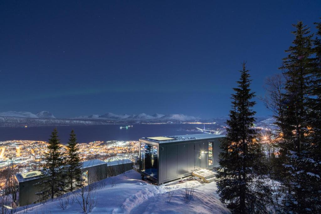 a building in the snow at night with a city at NARVIKFJELLET Camp 291 in Narvik