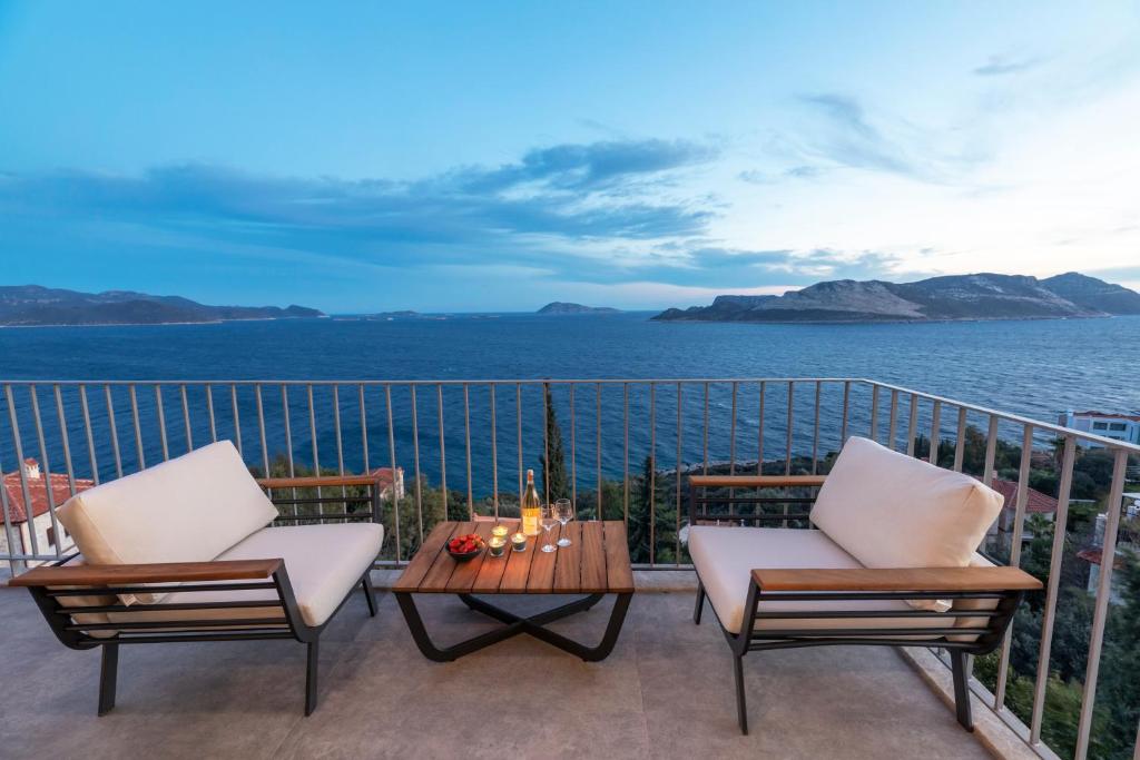 a balcony with two chairs and a table and the ocean at Born in Blue in Kaş