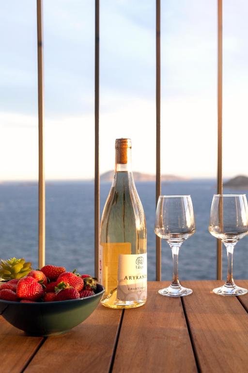 a bottle of wine and a bowl of fruit on a wooden table at Born in Blue in Kaş