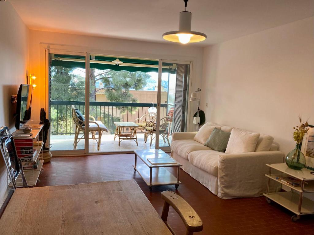 sala de estar con sofá y vistas a un patio en Superbe T3 dans les pins, terrasse sud, petite vue mer, plage à pieds, garage privé gratuit, en Les Lecques