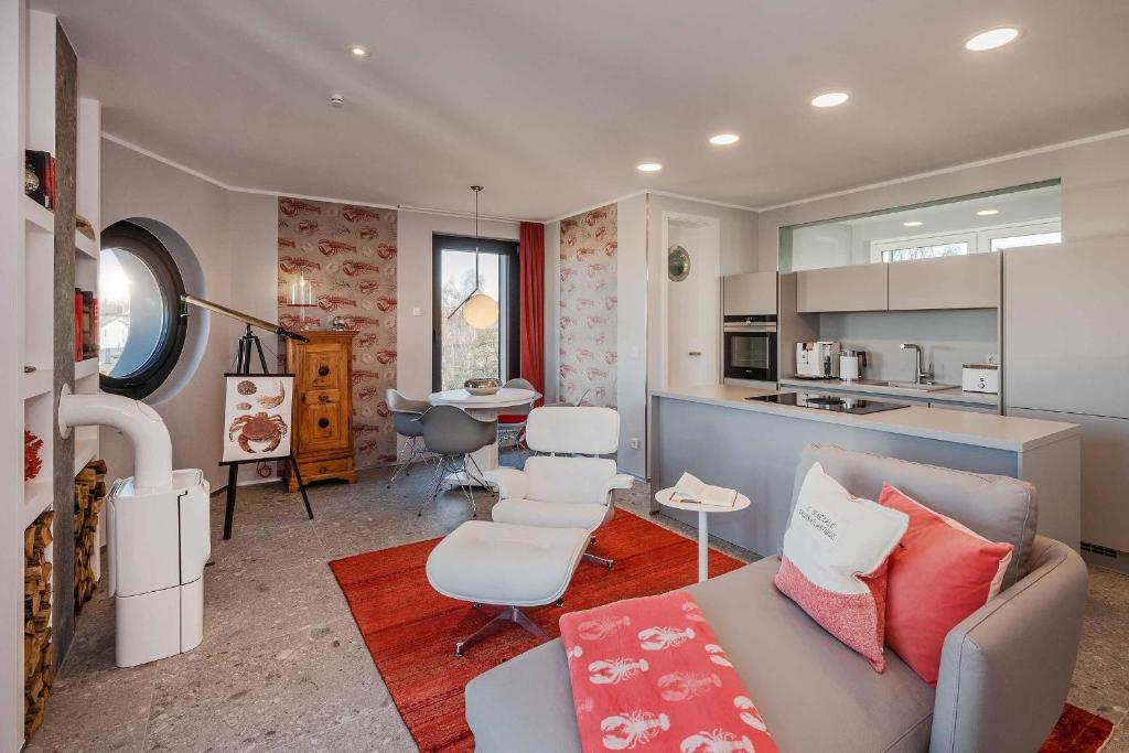 ein Wohnzimmer mit einem Sofa und Stühlen sowie eine Küche in der Unterkunft Lobster in Lubmin