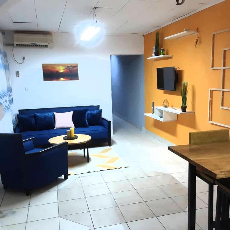 - un salon avec un canapé bleu et une table dans l'établissement Color house meublée sécurisée,100m Maképé palace, à Douala