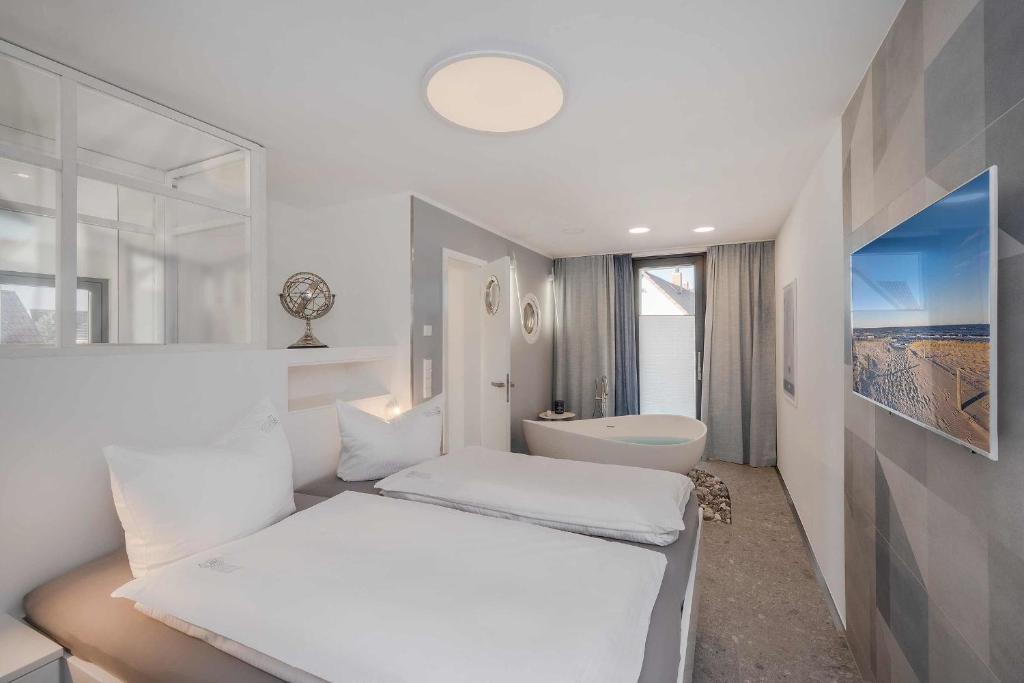 a white bedroom with a bed and a bath tub at Stormy in Lubmin
