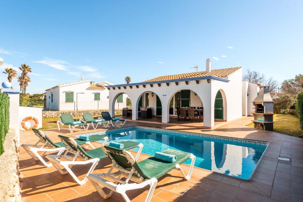 - une piscine avec des chaises et une maison dans l'établissement Villa Androna, à Cala'n Bosch