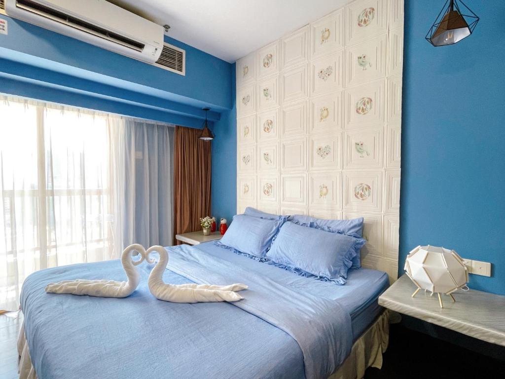 Dois cisnes sentados numa cama num quarto azul em Sunway Resort Suite @ Sunway Pyramid Lagoon View em Petaling Jaya