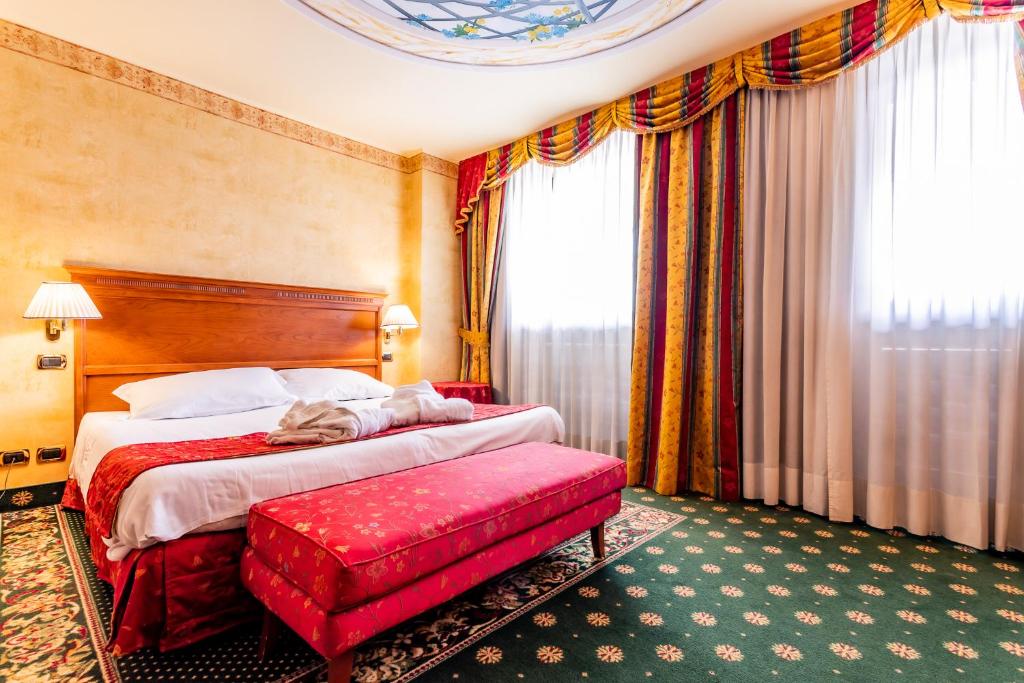um quarto de hotel com uma cama e um banco vermelho em Hotel Cristallo em Sestriere