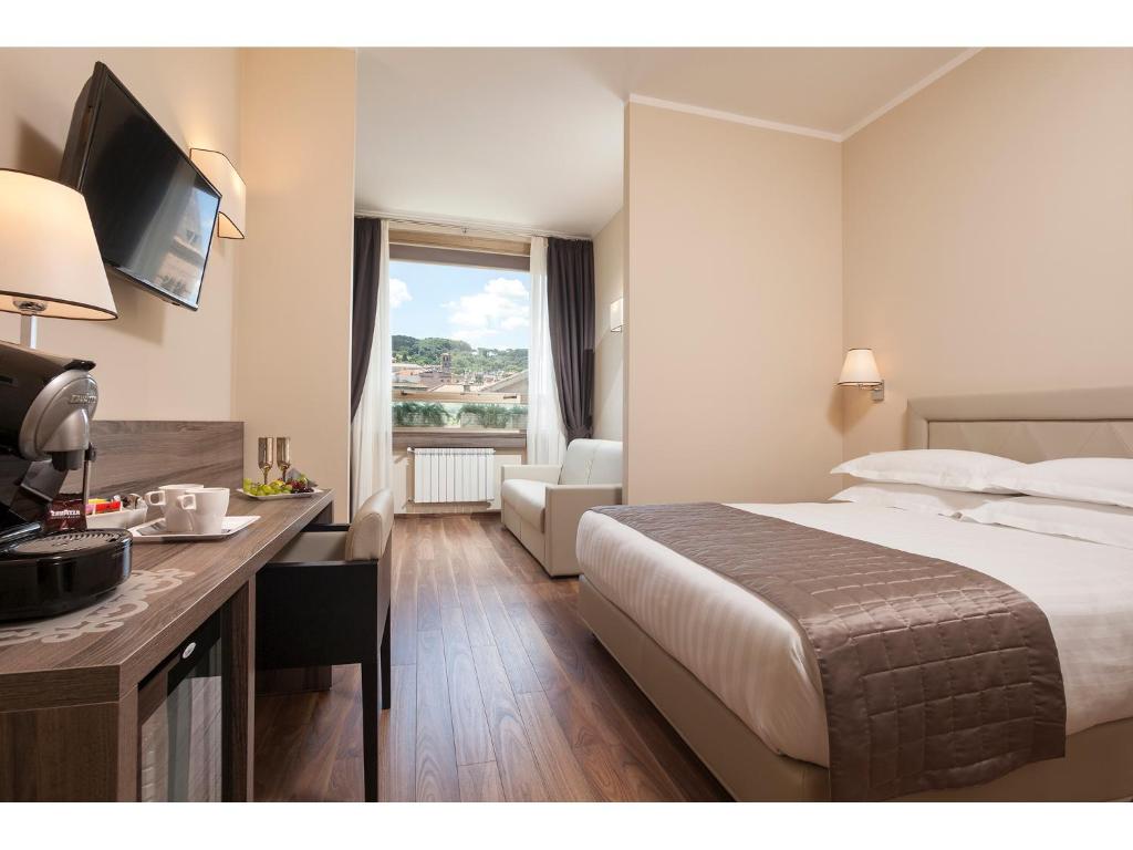ローマにあるWindow On Romeのベッド、デスク、テレビが備わるホテルルームです。
