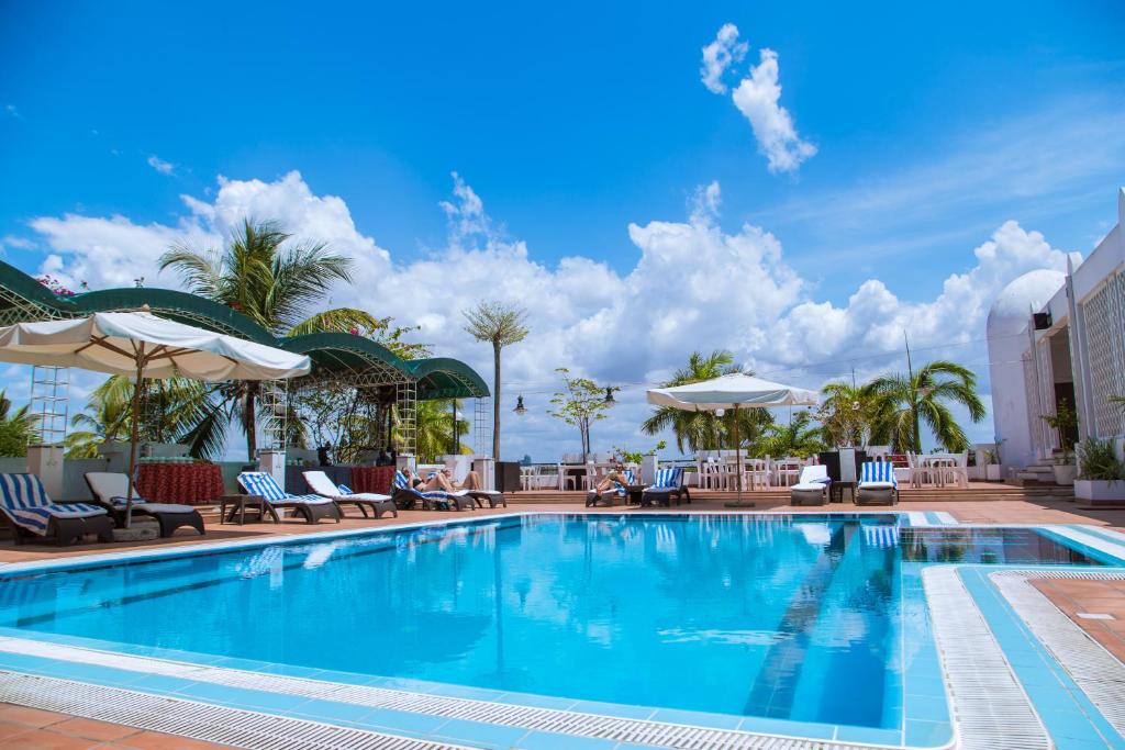 una piscina en un hotel con sillas y sombrillas en Hotel Slipway, en Dar es Salaam