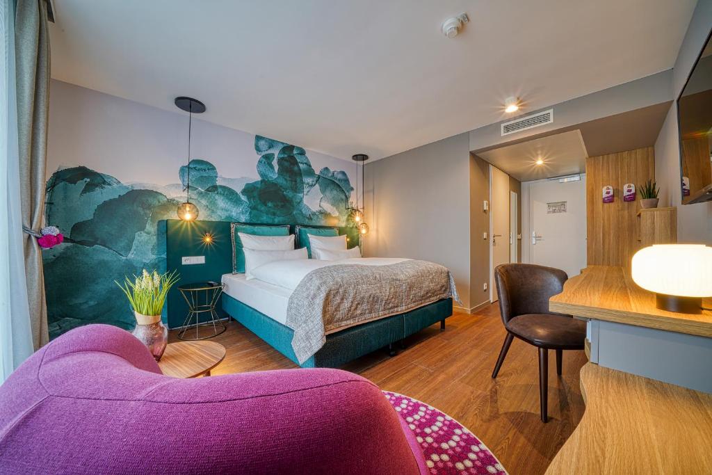 pokój hotelowy z łóżkiem i fioletową kanapą w obiekcie FourSide Hotel Freiburg we Fryburgu Bryzgowijskim