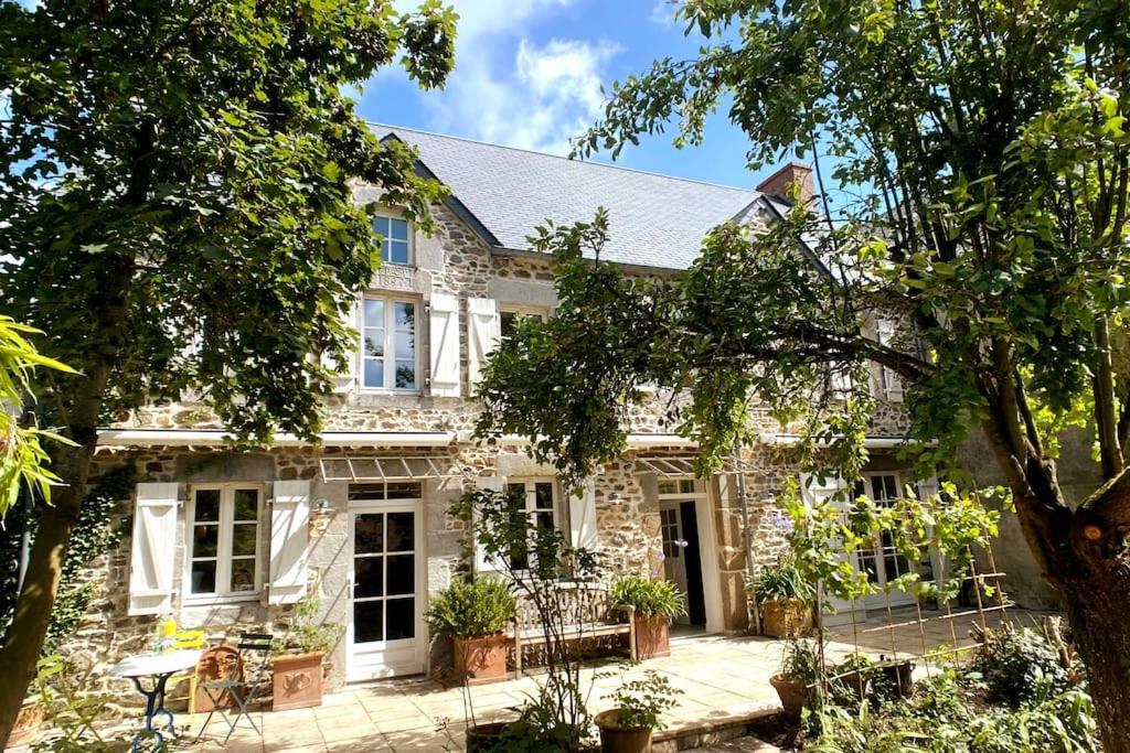 ein Steinhaus mit einer Terrasse davor in der Unterkunft Hübsches Landhaus der Familie mit eigenem Garten in Heugueville-sur-Sienne