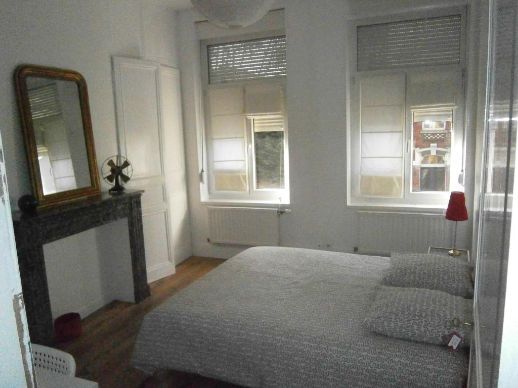 a bedroom with a bed and two windows at Bruneval House in Dunkerque