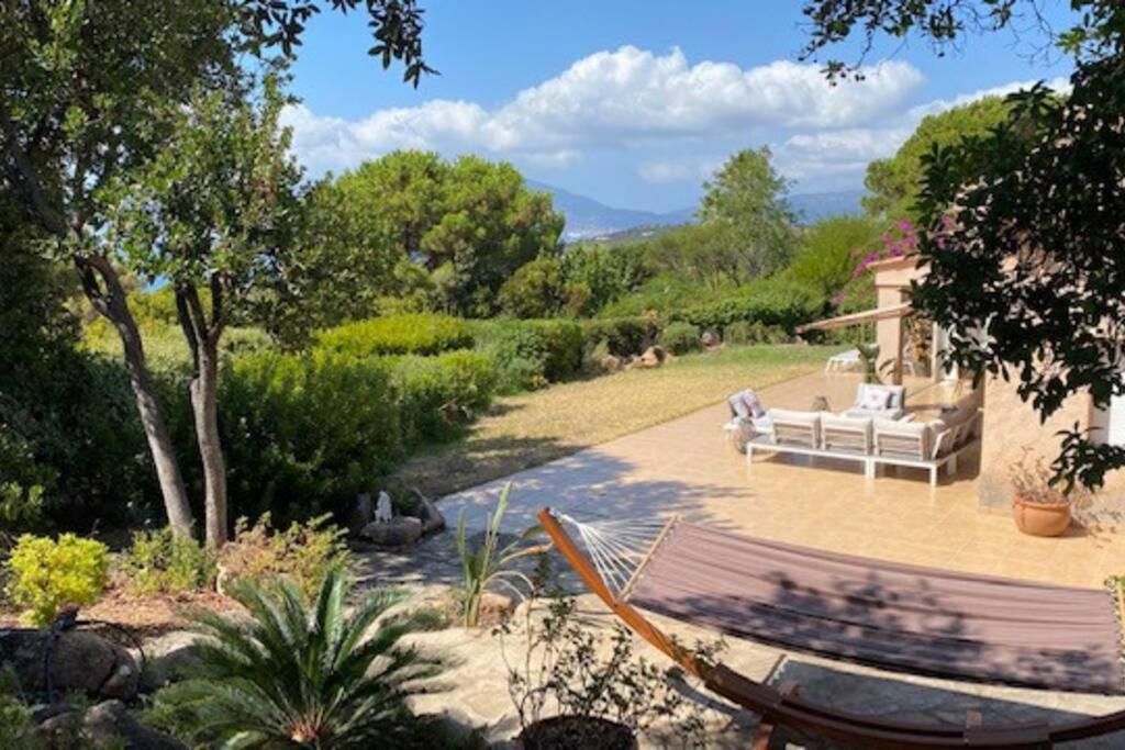 波爾蒂喬的住宿－Villa 180 m2 vue Mer au calme grand terrain Porticcio，花园内设有一个带沙发和吊床的庭院。