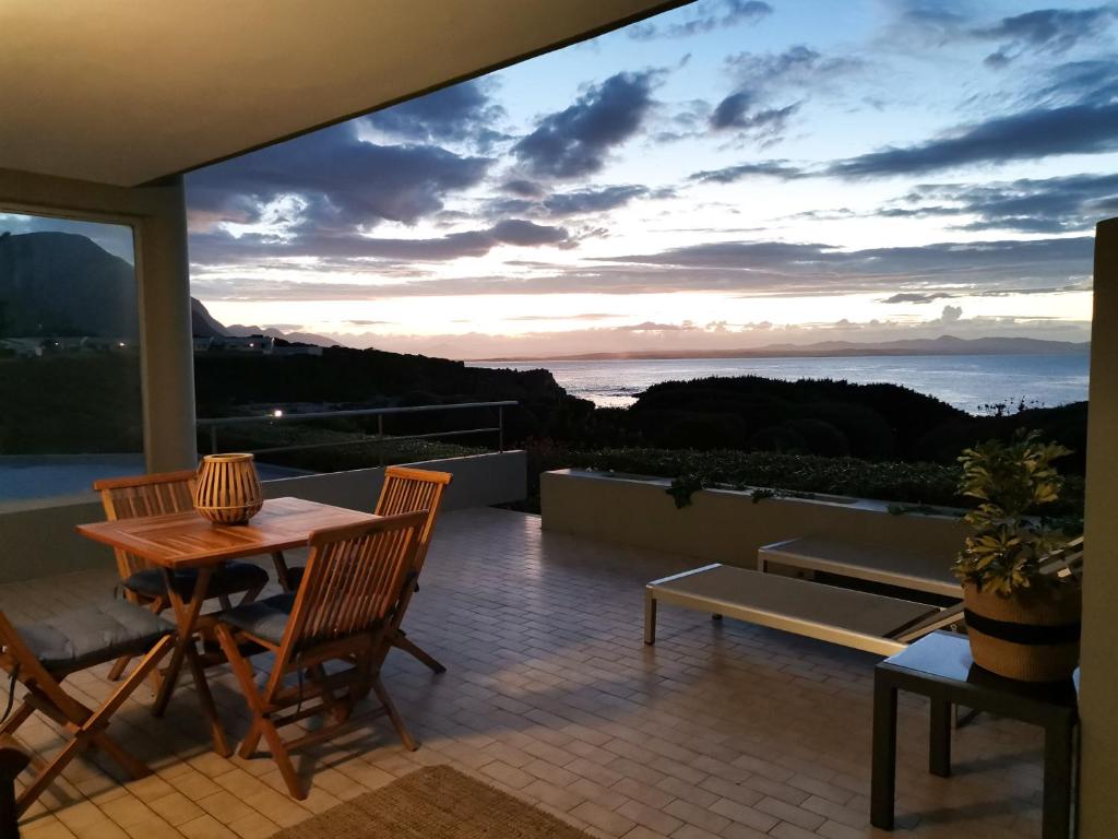 a patio with a table and chairs and a view of the ocean at Bayview 104 in Hermanus