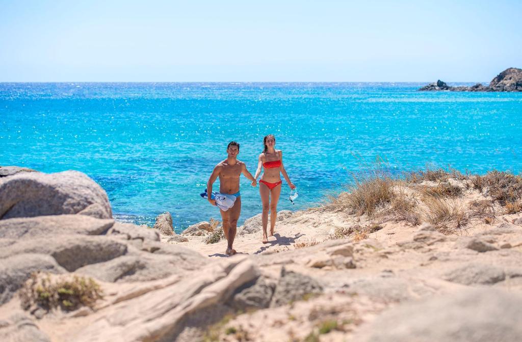 two people walking on the beach near the water at Chia Laguna - Hotel Village in Chia