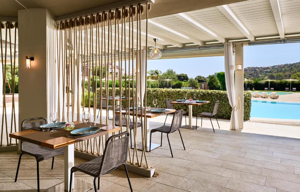 a patio with tables and chairs and a pool at Chia Laguna - Hotel Village in Chia