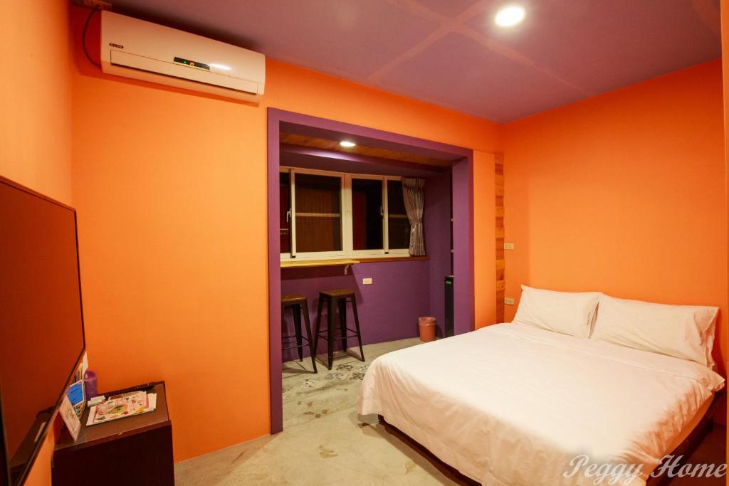 台東市的住宿－Peggy Home，一间卧室设有橙色墙壁和一张床