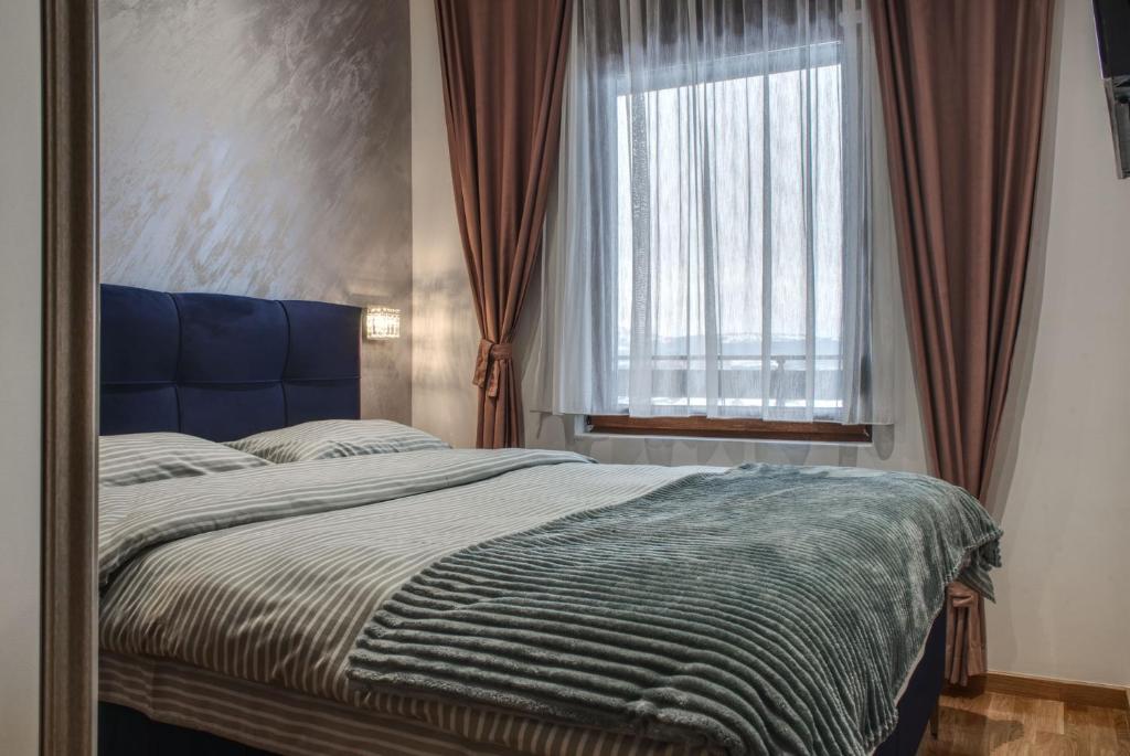 Schlafzimmer mit einem Bett und einem Fenster mit Vorhängen in der Unterkunft Zlatibor SKAJ&SPA in Zlatibor