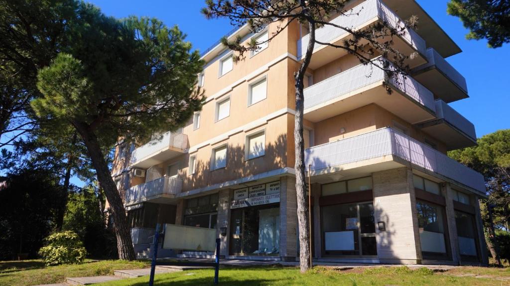 Un edificio de apartamentos con árboles en frente. en Rosa dei Venti, en Lignano Sabbiadoro
