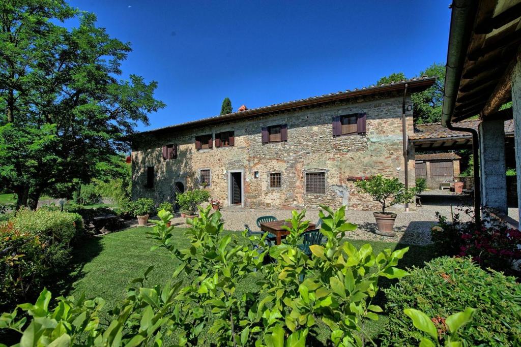 une ancienne maison en pierre avec un jardin en face de celle-ci dans l'établissement Casale Giotto by PosarelliVillas, à Vicchio