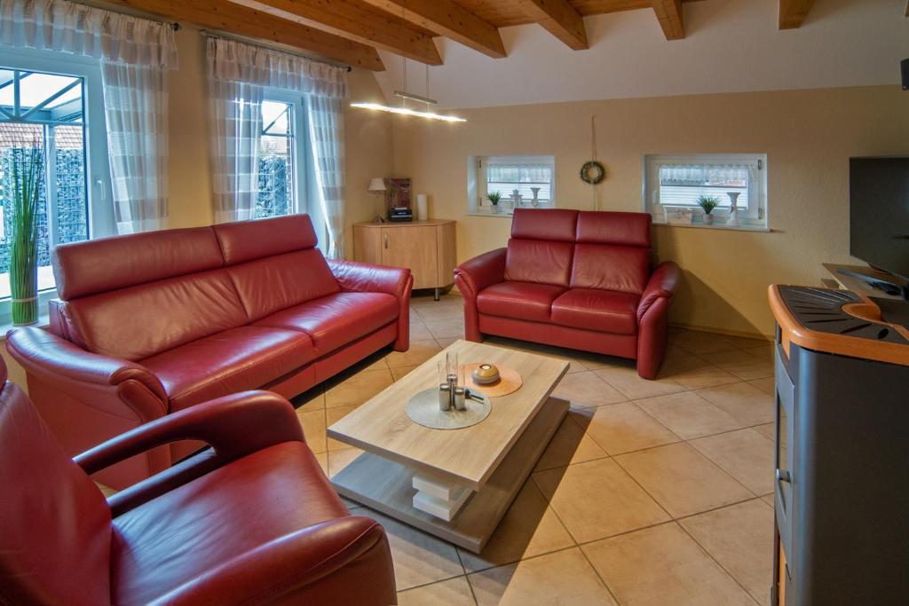 una sala de estar con muebles de cuero rojo y una mesa. en Friedas Huus, en Nessmersiel
