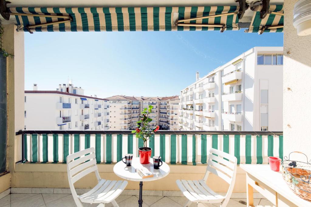 a table and chairs on a balcony with a view of buildings at ELEGANCE YourHostHelper in Le Cannet