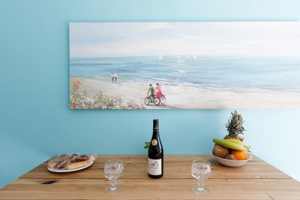 a bottle of wine on a table with a picture of the beach at ELEGANCE YourHostHelper in Le Cannet