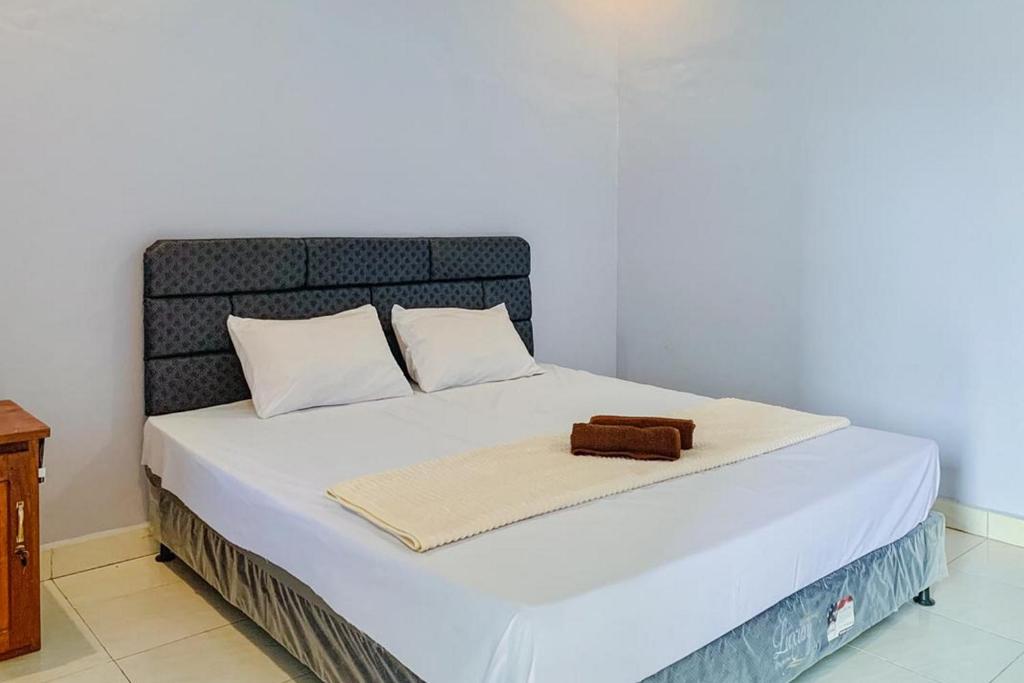 Una cama con sábanas blancas y una bolsa marrón. en Embun Rinjani Homestay, en Senaru