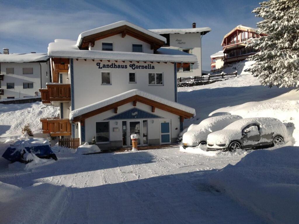 dos autos estacionados en la nieve frente a un edificio en Landhaus Cornelia, en Berwang