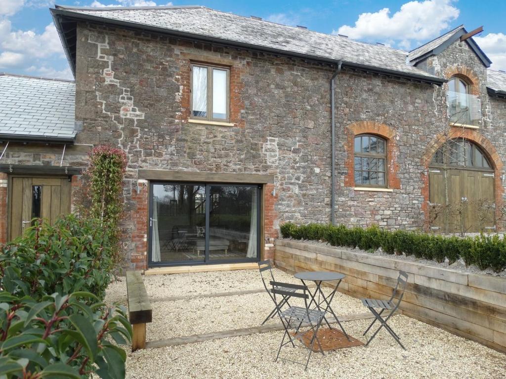 a brick house with two chairs and a table at Gardeners Cottage in Talaton