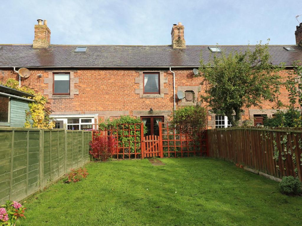 a brick house with a fence and a yard at Sea Lily in Cheswick