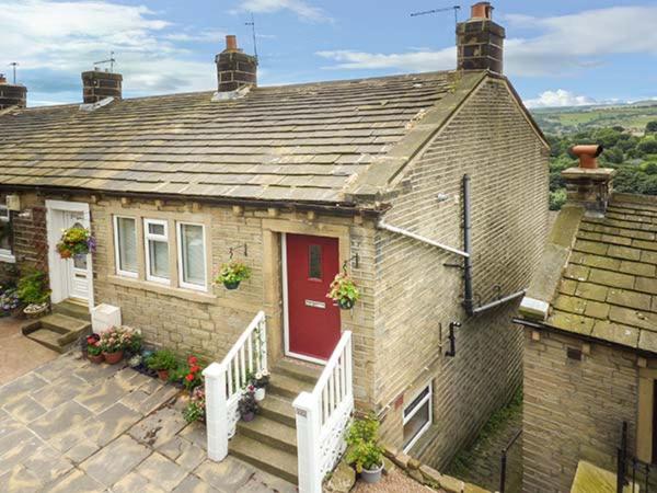 a brick house with a red door and a porch at Ginnel Corner in Golcar