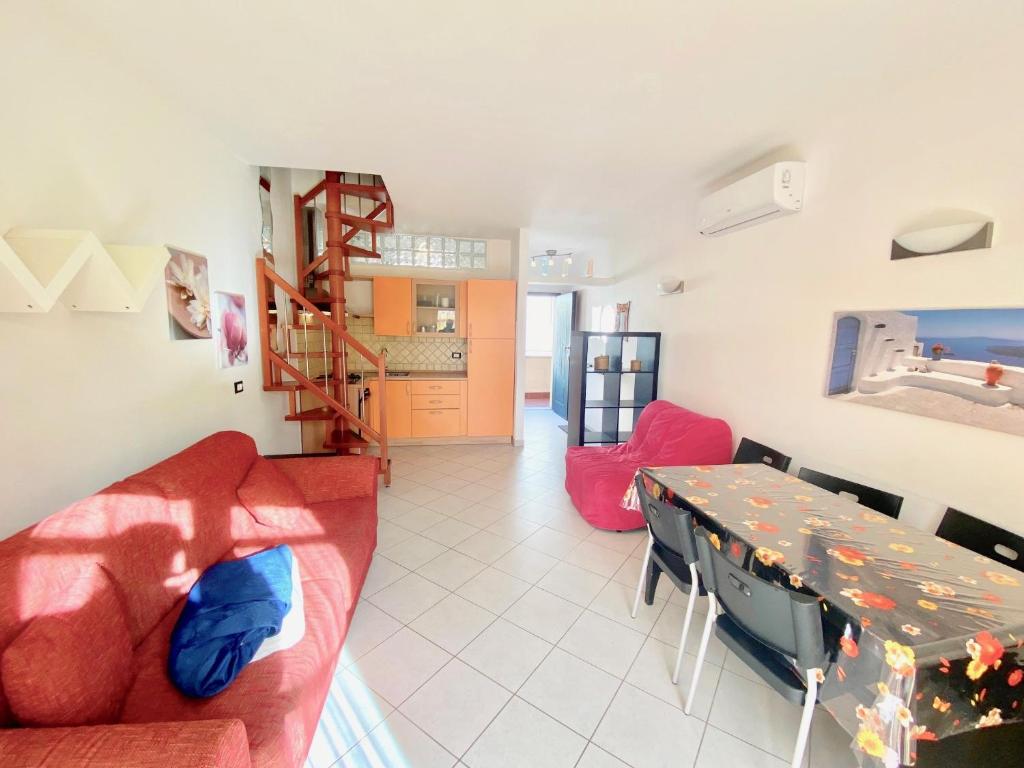 ein Wohnzimmer mit einem roten Sofa und einem Tisch in der Unterkunft Bilocale Via del Mare in Marina di Bibbona