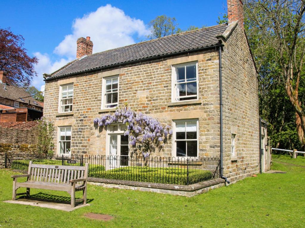 a brick house with a bench in front of it at The Green in Lastingham