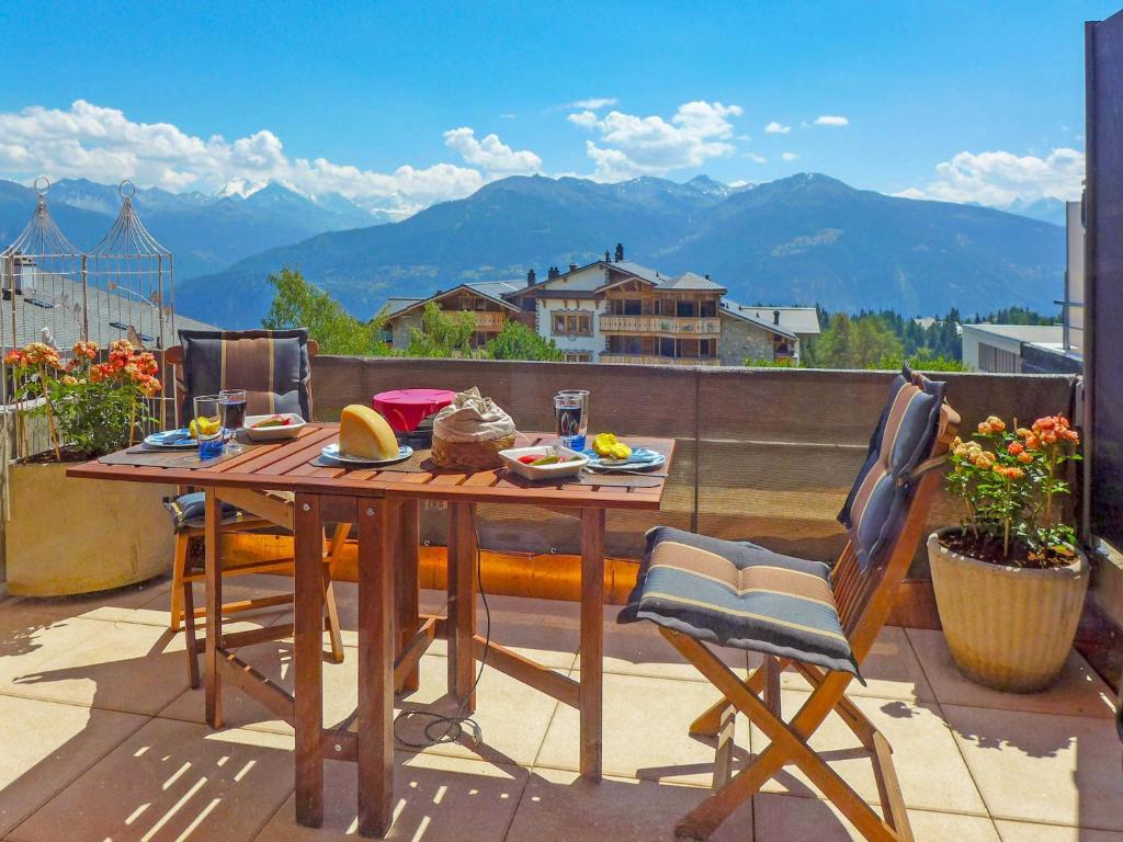 a table and chairs on a balcony with a view of mountains at Studio Jeanne d'Arc-9 by Interhome in Crans-Montana