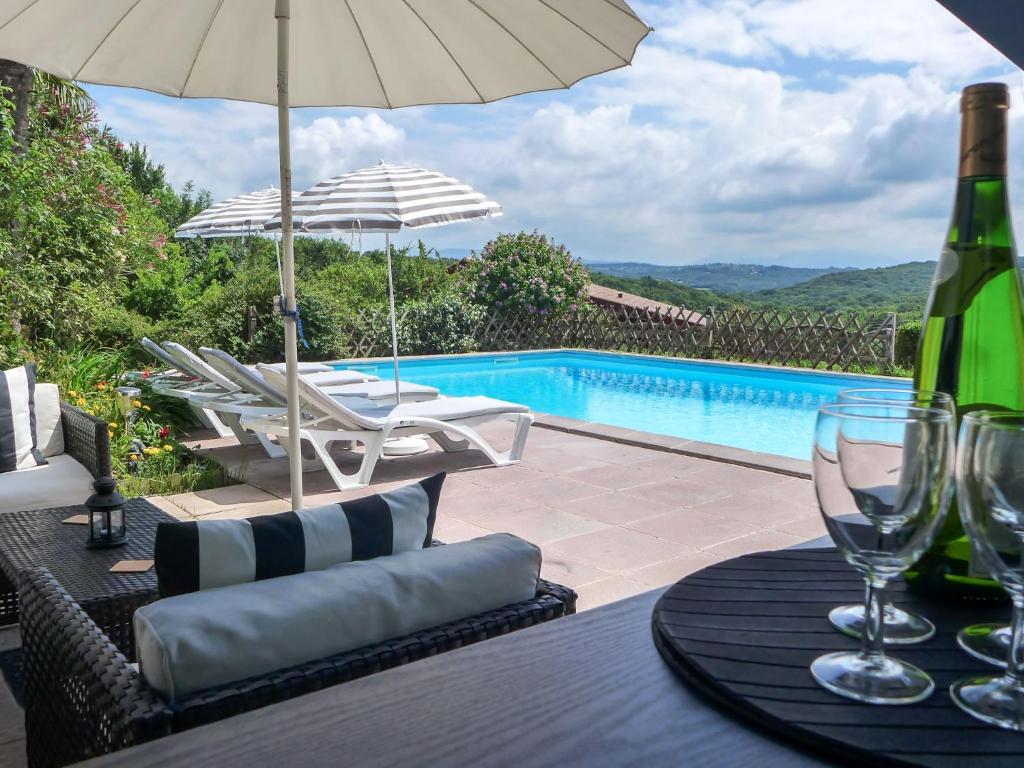 a table with wine glasses and an umbrella next to a pool at Villa Landaboure by Interhome in Urcuit