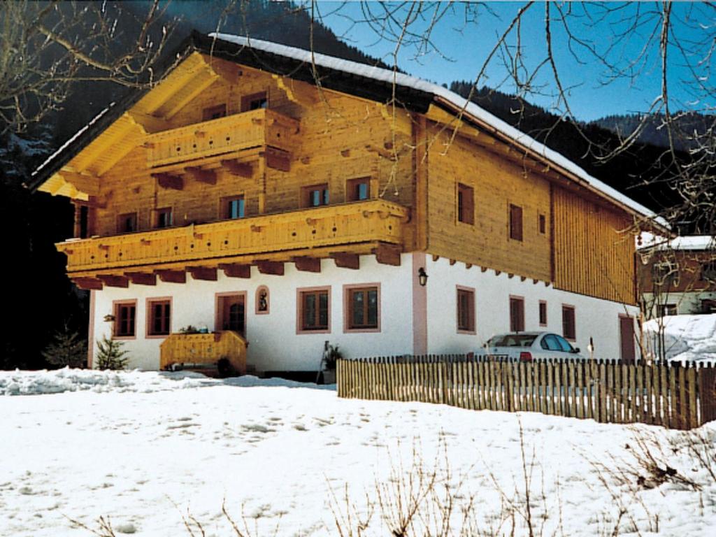 uma grande casa de madeira na neve com uma cerca em Apartment Luftbichl - SLB130 by Interhome em Viehhofen