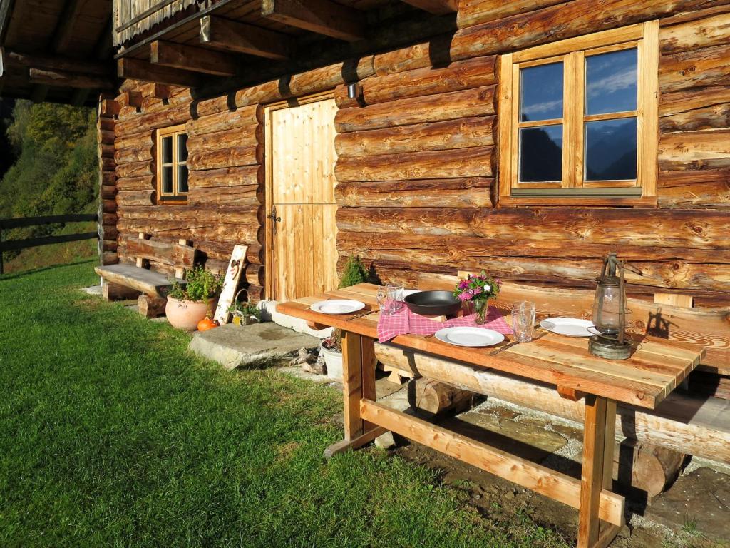 a picnic table in front of a log cabin at Chalet Sturmbachhütte - UTD110 by Interhome in Uttendorf